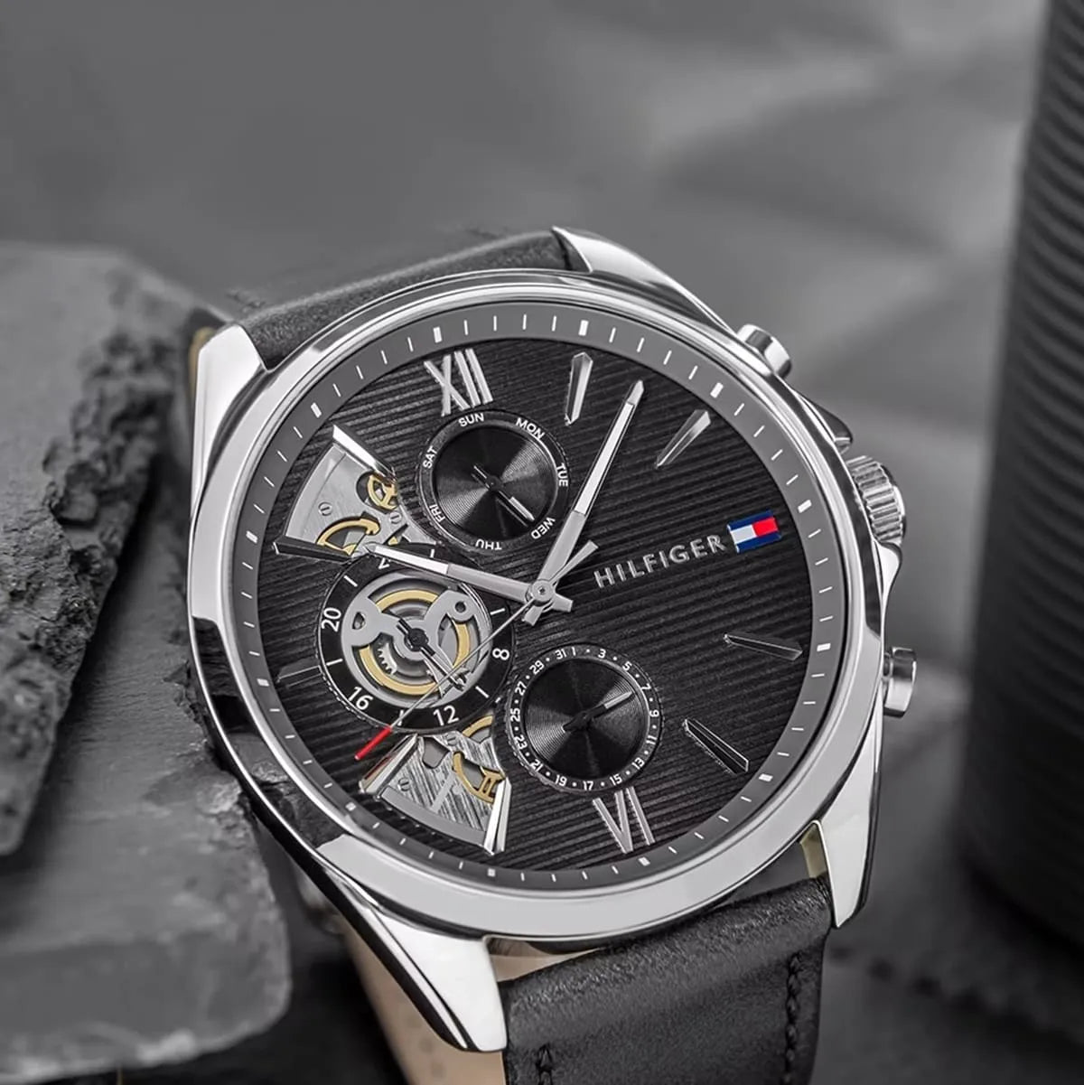 Close-up detail of Damon watch dial showing Roman numerals, visible movement, and chronograph subdials