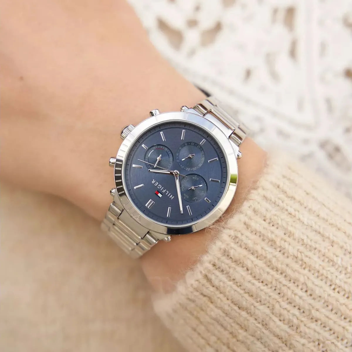 Tommy Hilfiger women's watch on wrist showing blue dial, chronograph subdials, and metal bracelet