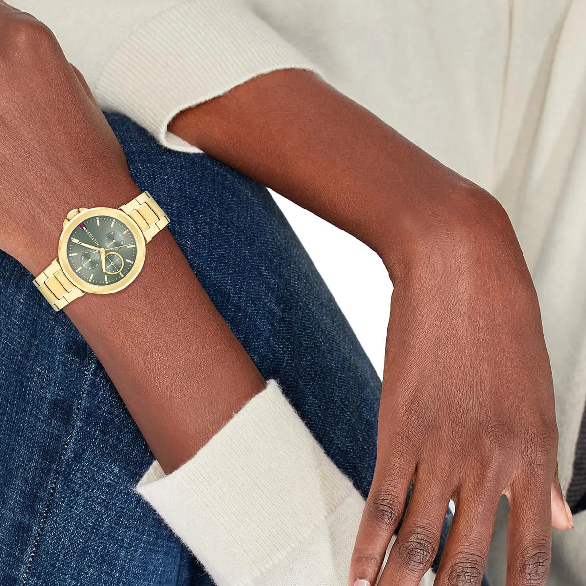 Tommy Hilfiger gold watch with green dial worn on wrist with navy and white clothing