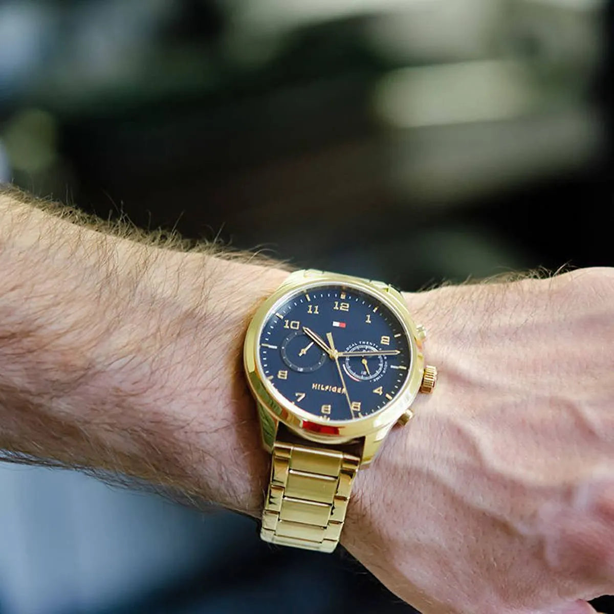 Gold Tommy Hilfiger watch worn on wrist with blue dial and dual time display