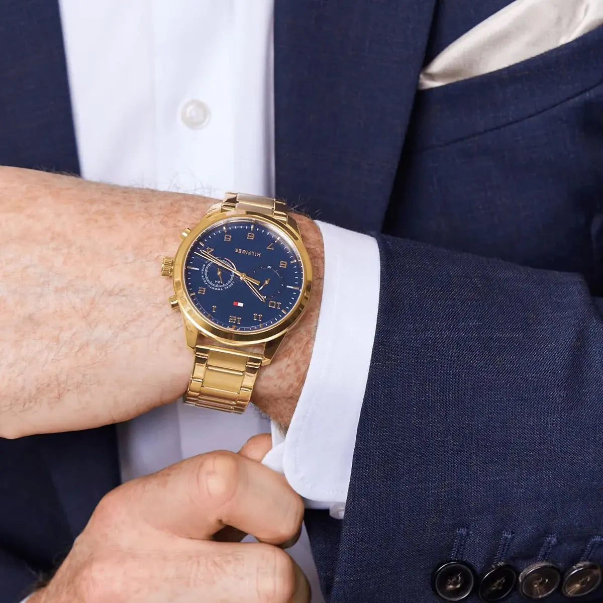 Gold Tommy Hilfiger dual time watch worn on wrist with formal attire