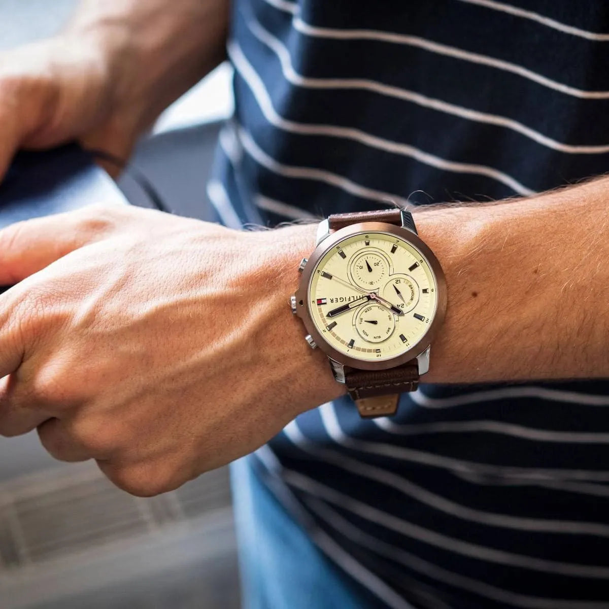 Tommy Hilfiger watch worn on wrist showing beige dial and brown leather strap