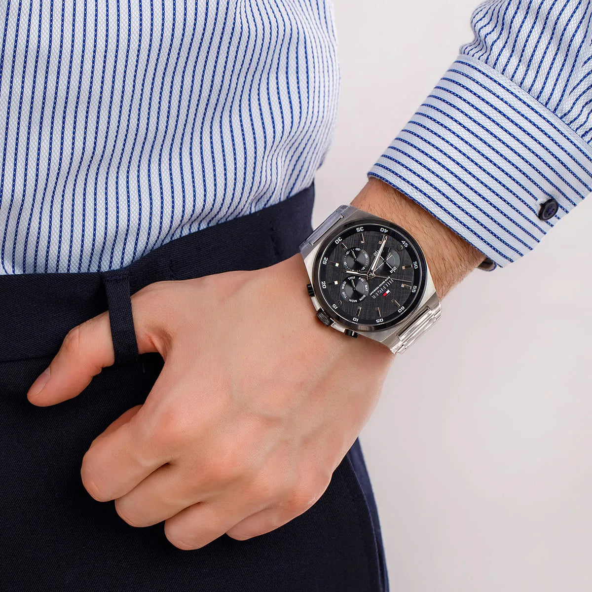 Tommy Hilfiger Dexter multifunction watch worn on wrist with striped blue shirt