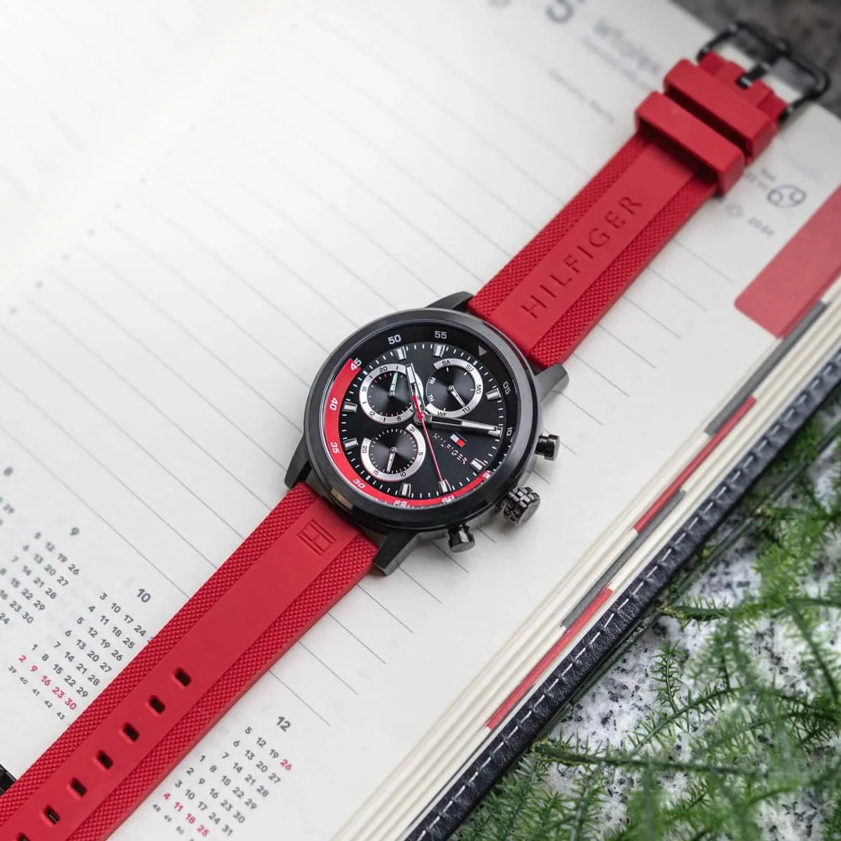 Tommy Hilfiger ROCKY watch worn on wrist with red rubber strap on calendar background