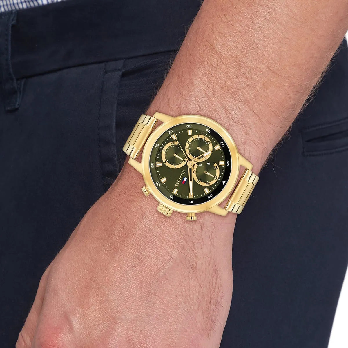 Tommy Hilfiger multifunction watch on wrist showing green dial with gold-tone case and bracelet