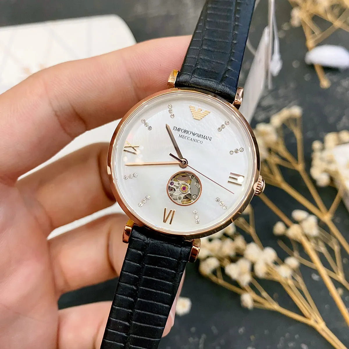 Emporio Armani Gianni T-Bar watch held in hand showing white mother-of-pearl dial detail