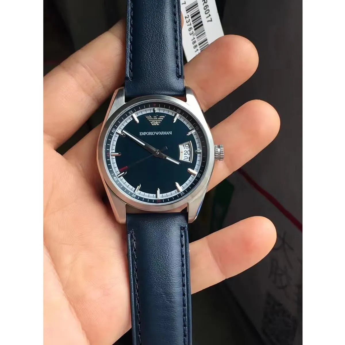 AR6017 New Tazio watch in hand showing blue dial, date window, and navy leather strap