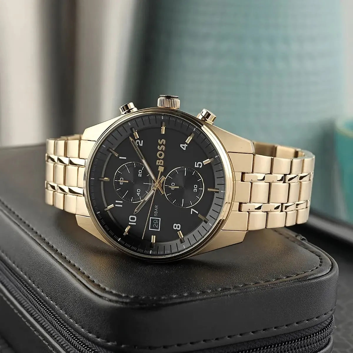 BOSS Ambassador chronograph watch worn on wrist showing black dial and gold metal bracelet