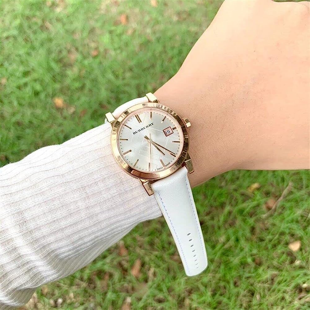 Burberry rose gold watch with white leather strap worn on wrist