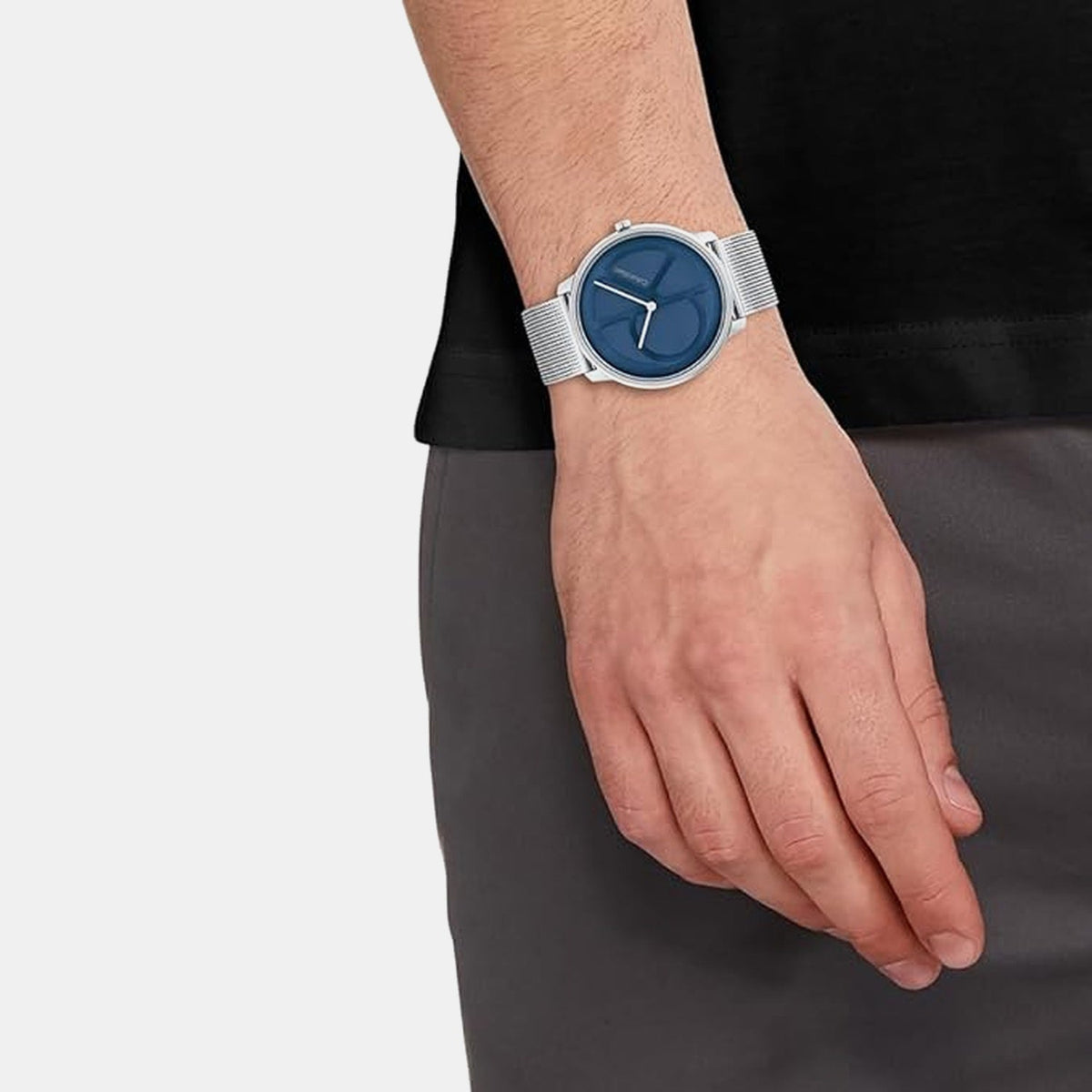 Calvin Klein silver mesh watch with blue dial worn on wrist