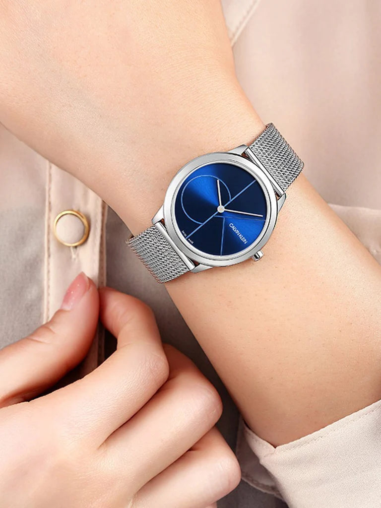 Calvin Klein Minimal watch with blue dial on woman's wrist, showing silver mesh bracelet