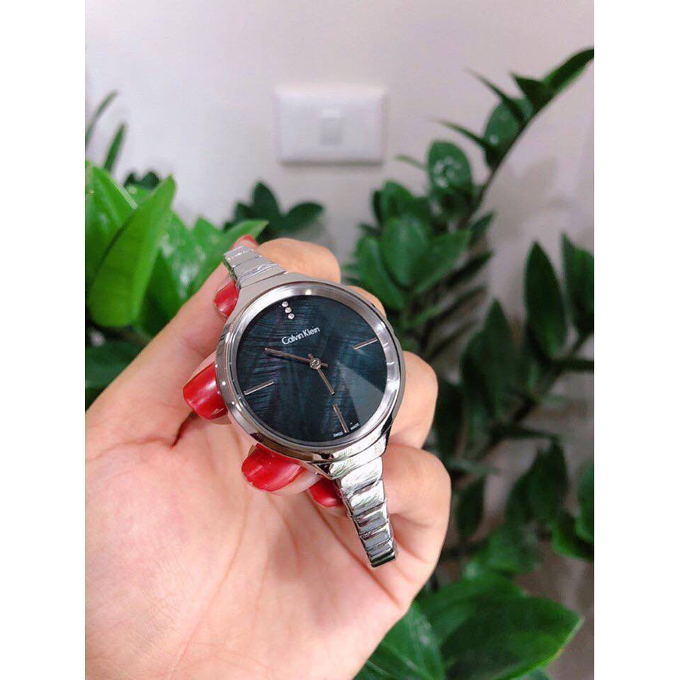 Calvin Klein LIVELY women's watch held in hand showing black dial and steel case