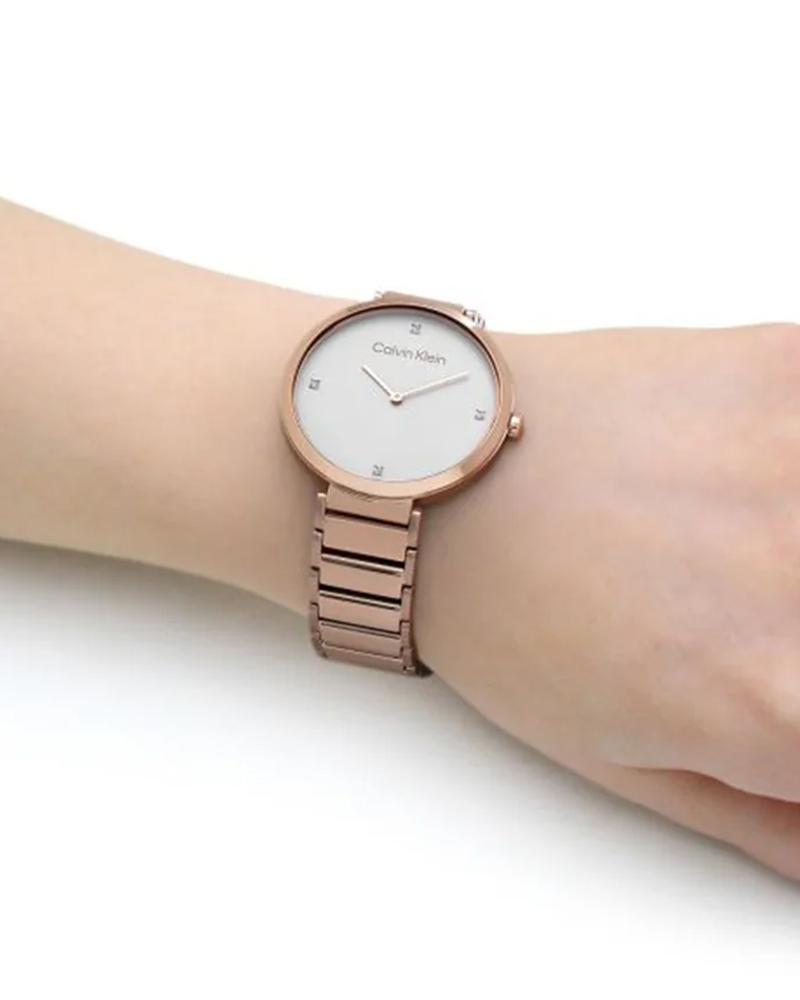 Calvin Klein Minimalistic gold-tone women's watch worn on wrist with white dial and diamond indices