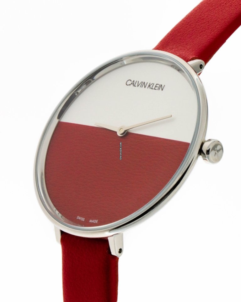 Close-up angled view of Calvin Klein Rise watch dial with silver hands and red strap