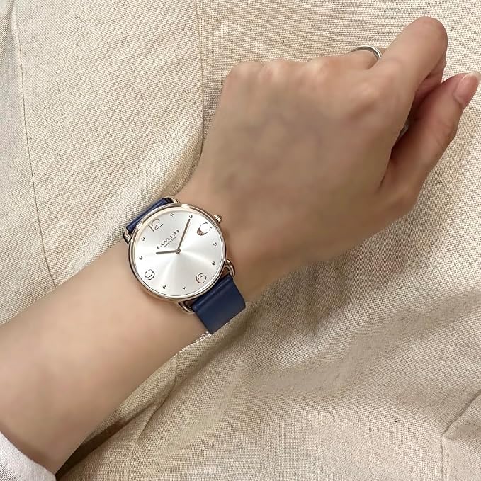 COACH women's round watch with white dial and blue leather strap worn on wrist