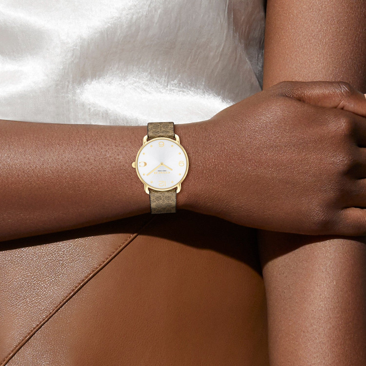 Coach Elliot watch worn on wrist displaying silver dial with gold numerals and tan canvas strap