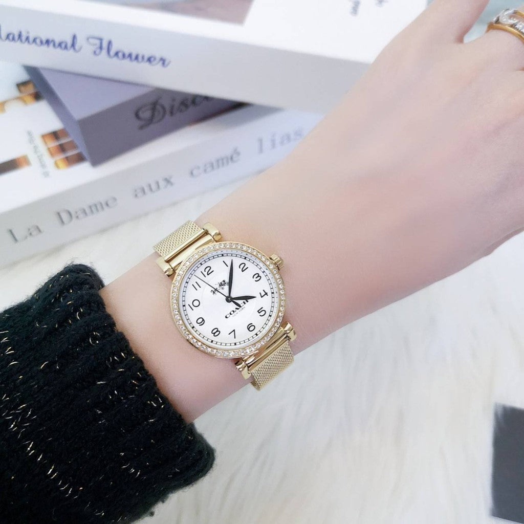 Coach Madison gold watch worn on wrist showing crystal bezel and white dial