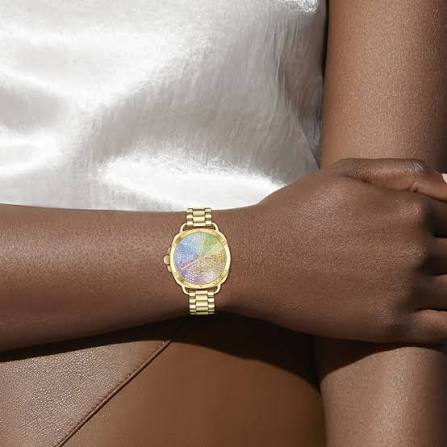 COACH Tatum yellow gold watch worn on wrist with multi-color crystal dial