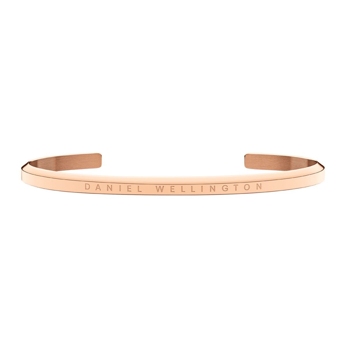 Rose gold cuff bracelet with Daniel Wellington engraved text, shown flat against green background