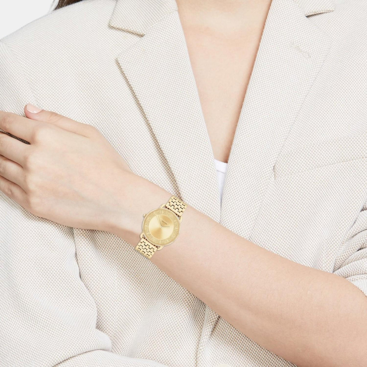 Elliot gold watch worn on wrist with gold link bracelet