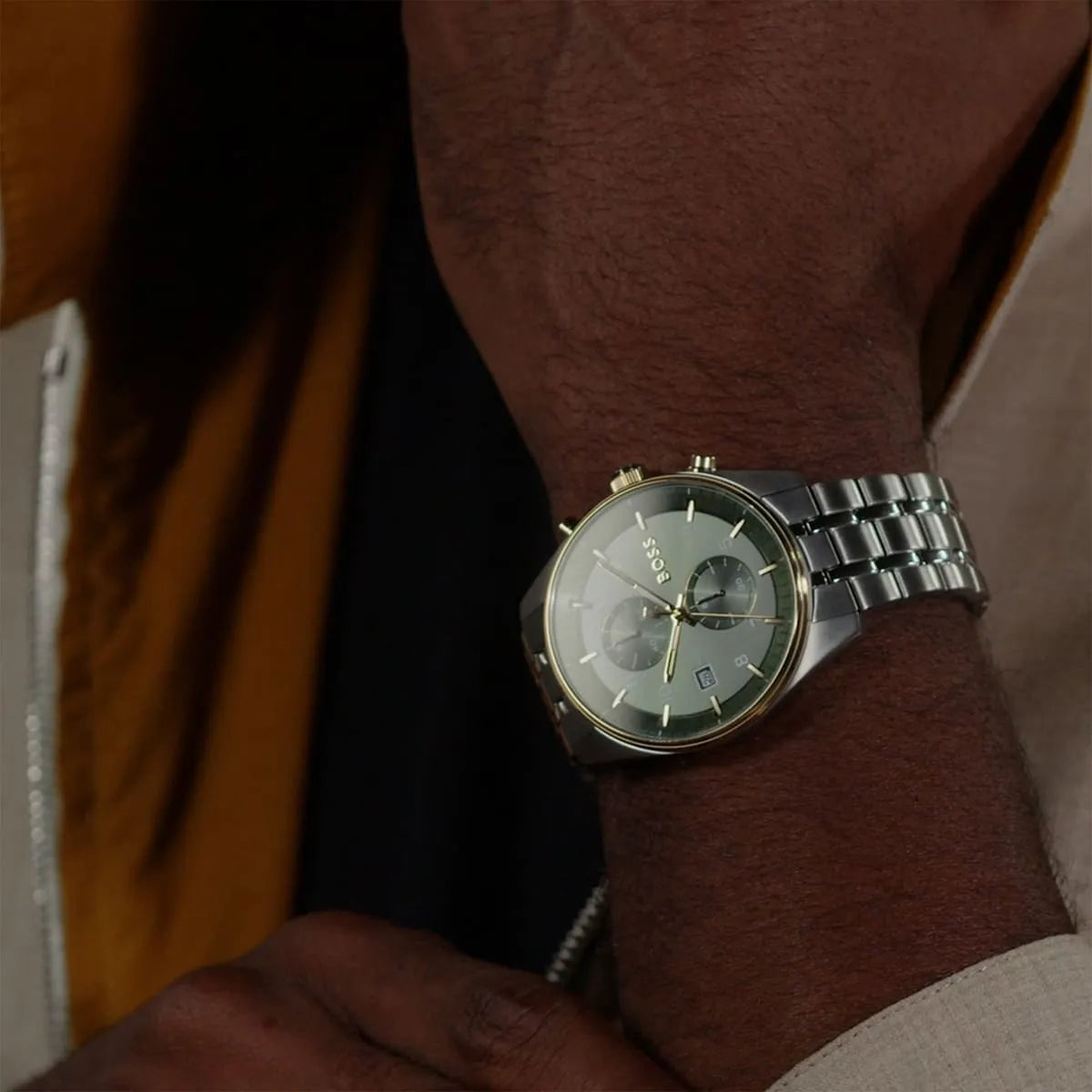 Hugo Boss green dial chronograph watch worn on man's wrist showing stainless steel bracelet