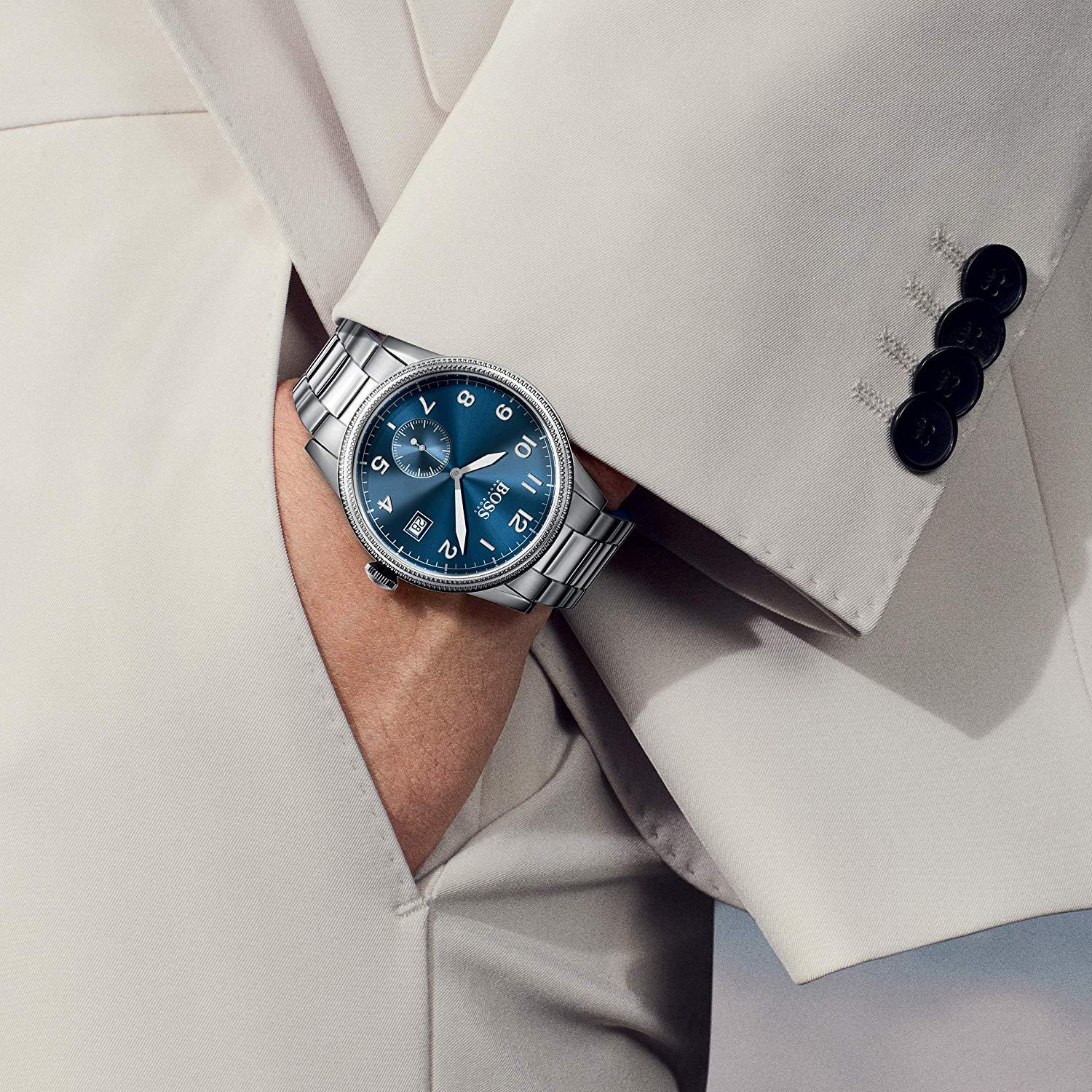 Hugo Boss blue dial watch worn on wrist with silver bracelet against light colored sleeve