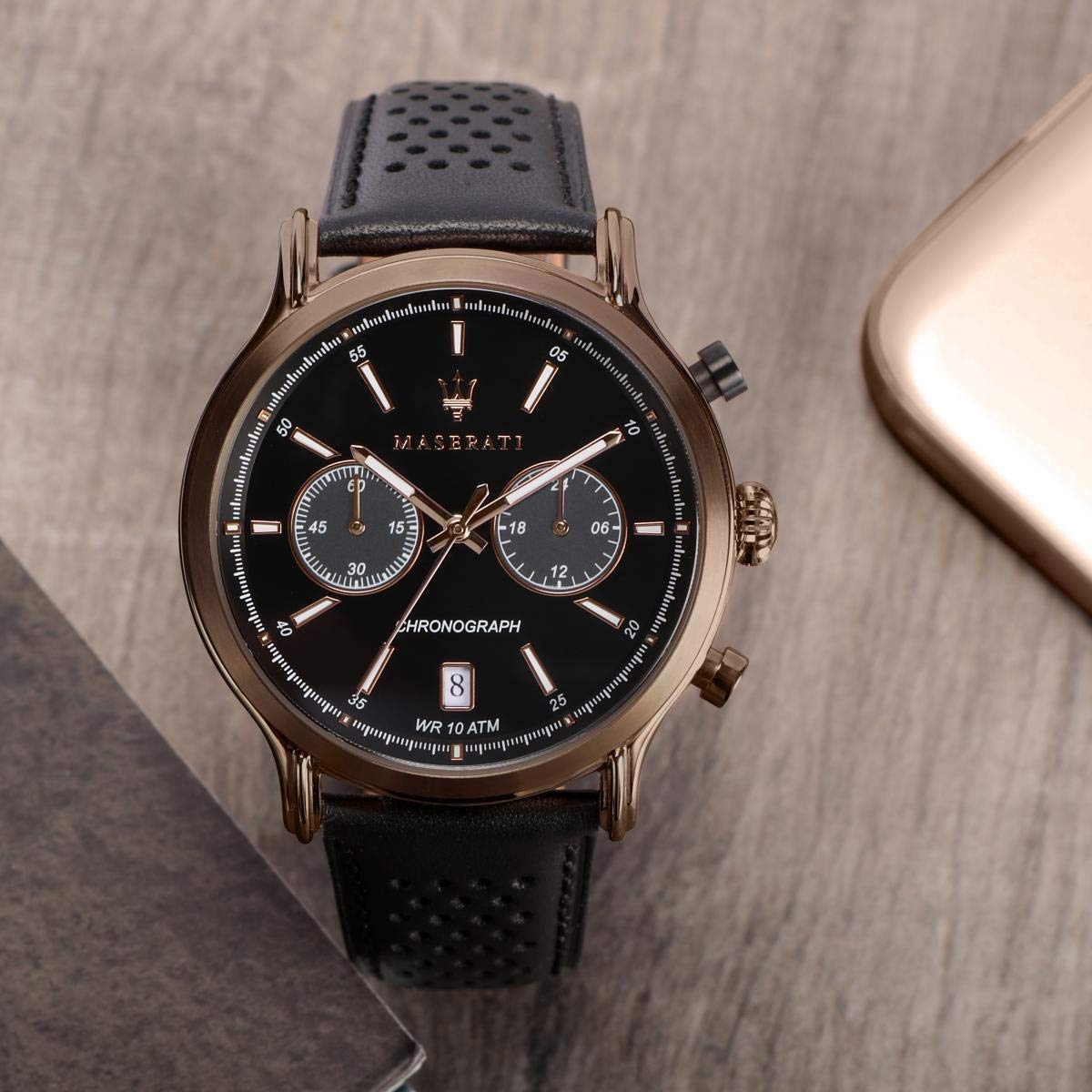 Maserati watch with black dial displayed next to mobile phone