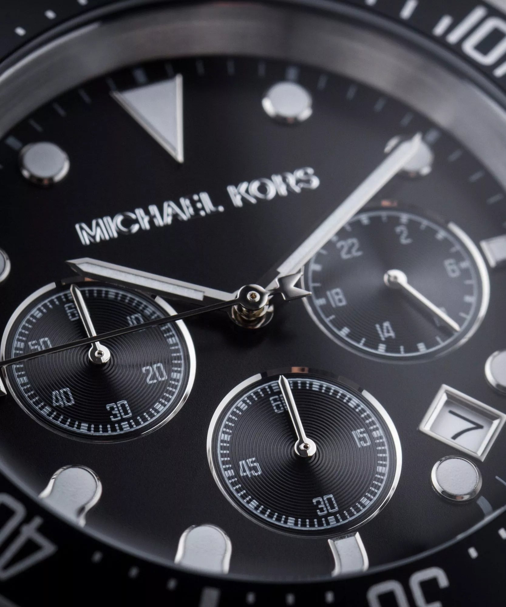 Close-up of black chronograph dial with three subdials and Michael Kors branding