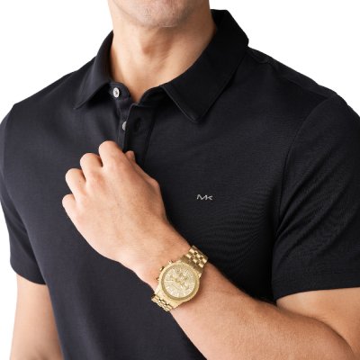 Michael Kors MK8953 Hutton gold-tone watch worn on wrist with black polo shirt