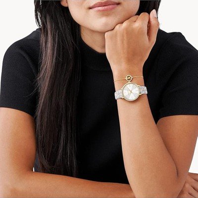 Michael Kors Pyper MK1037 watch worn on wrist showing gold case and cream patterned leather strap on wearer