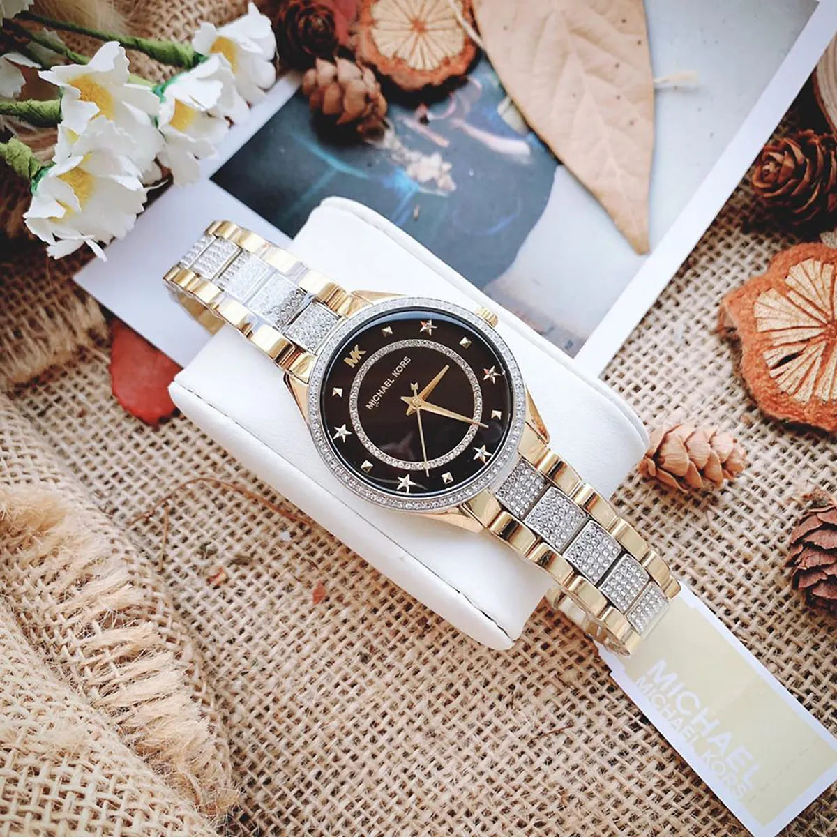 Michael Kors Lauryn watch styled with home decor showing black dial and two-tone strap