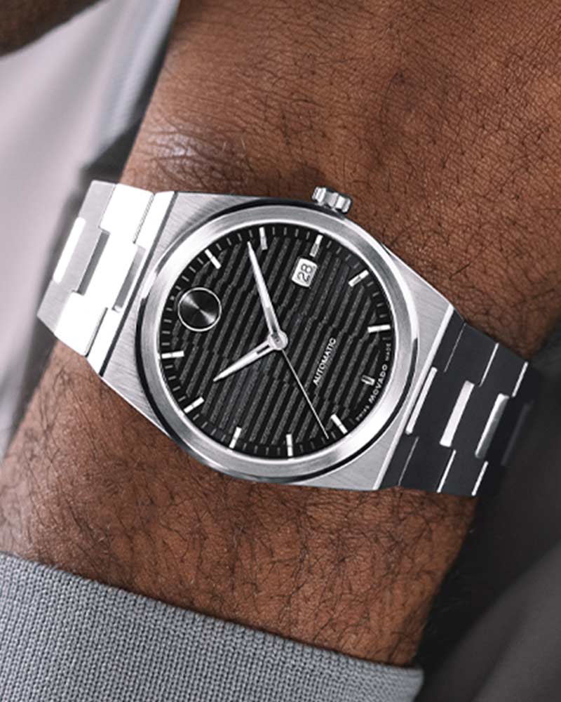 Movado BOLD Quest automatic watch worn on wrist showing black dial with date window and stainless steel bracelet