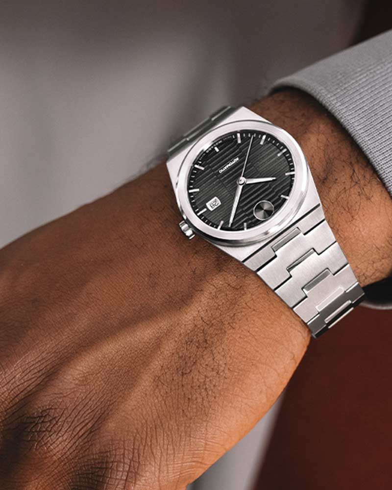 Movado BOLD Quest watch on wrist displaying integrated stainless steel bracelet and black dial design