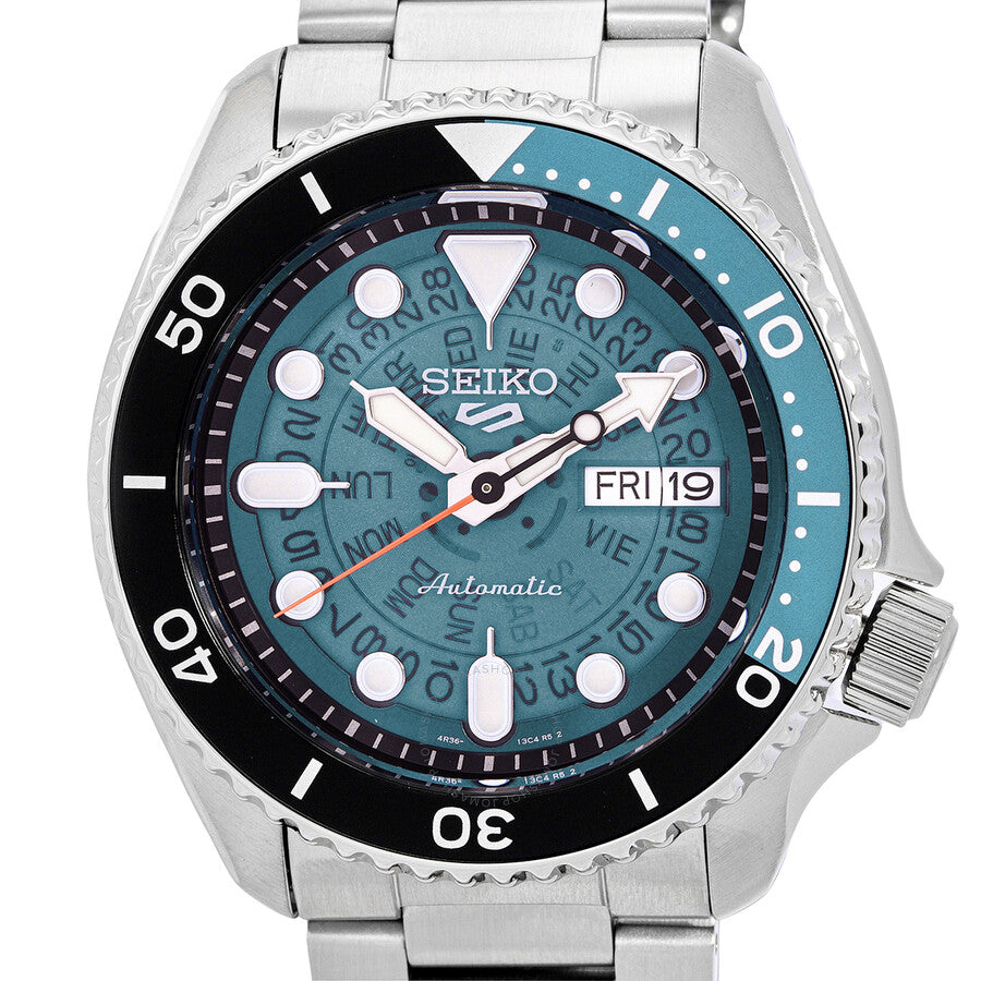 Close-up detail of teal dial featuring Seiko branding, white applied markers, day-date window, and hands