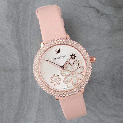 Close-up of Swarovski watch dial featuring white background with pink flowers and decorative crystal elements