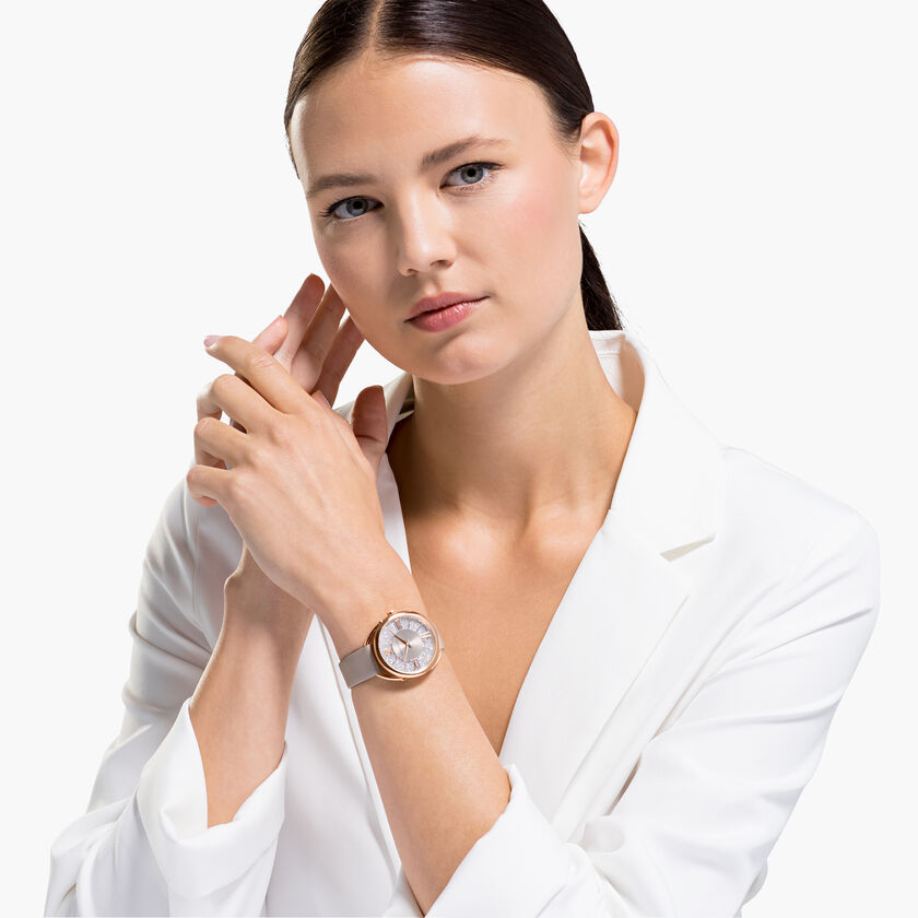 Crystalline Glam watch worn on wrist, showing rose gold case and crystal dial on grey strap