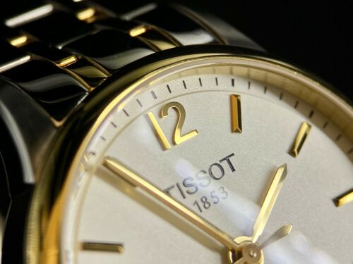 Close-up detail of Tissot Chemin Des Tourelles white dial with gold hour markers and TISSOT 1853 branding