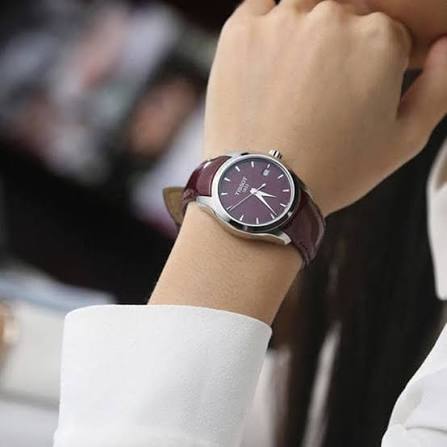 Tissot Couturier quartz watch on wrist showing burgundy dial and burgundy leather strap