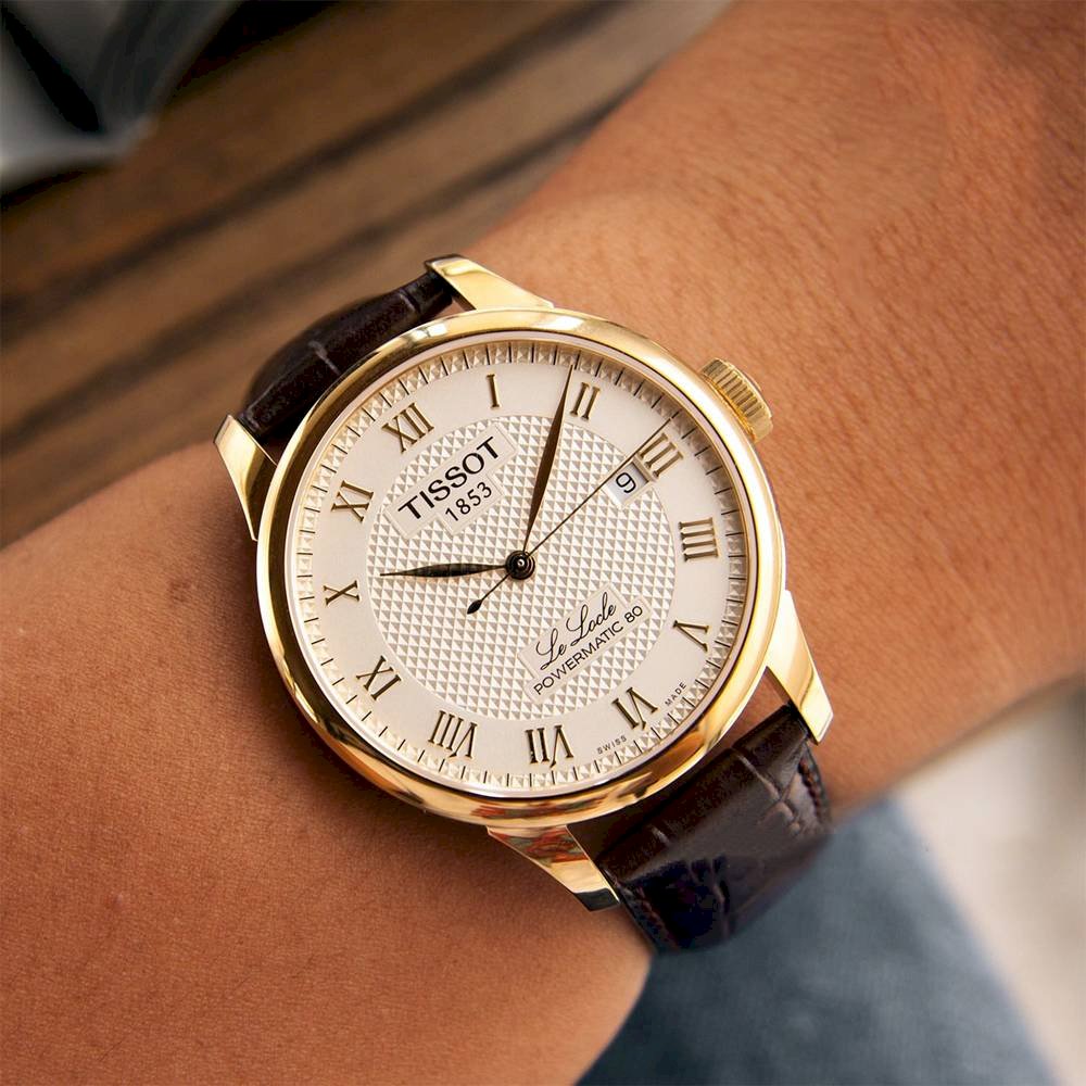 Tissot Le Locle automatic watch on wrist showing gold case and brown strap detail