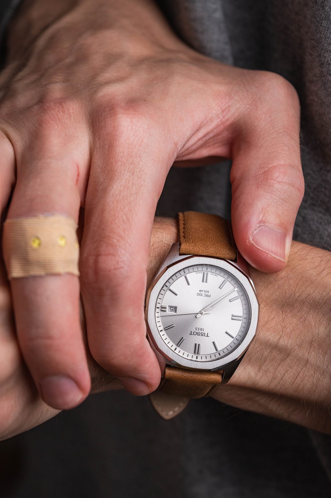 Tissot PRC100 watch worn on wrist displaying silver dial and brown leather strap