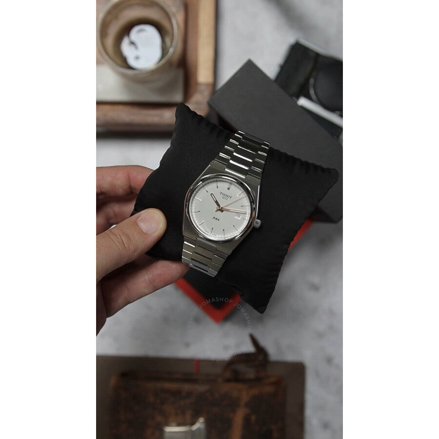 Tissot PRX quartz watch on wrist, displayed on black fabric with retail packaging