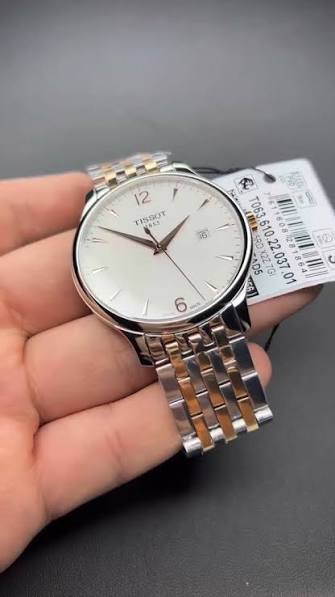 Tissot Tradition watch in hand with product tag, displaying dial and two-tone bracelet