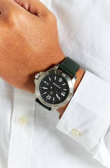 Tommy Hilfiger watch worn on wrist with green leather strap and black dial