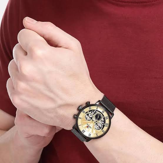 Tommy Hilfiger multifunction watch worn on wrist with golden dial and black mesh strap