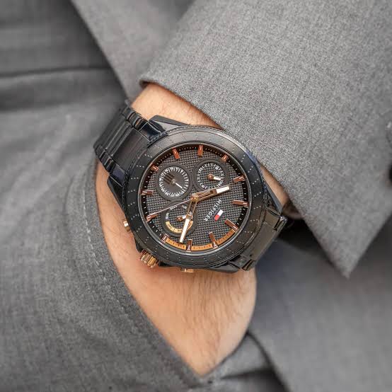 Tommy Hilfiger Aiden black chronograph watch worn on wrist with gray suit sleeve