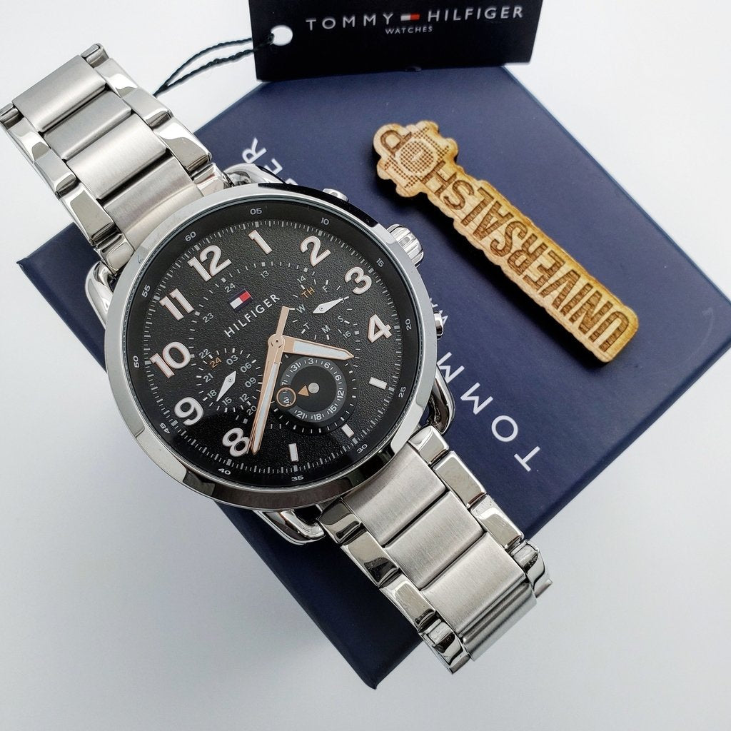 Tommy Hilfiger Briggs watch displayed with navy presentation box, gold charm, and booklet