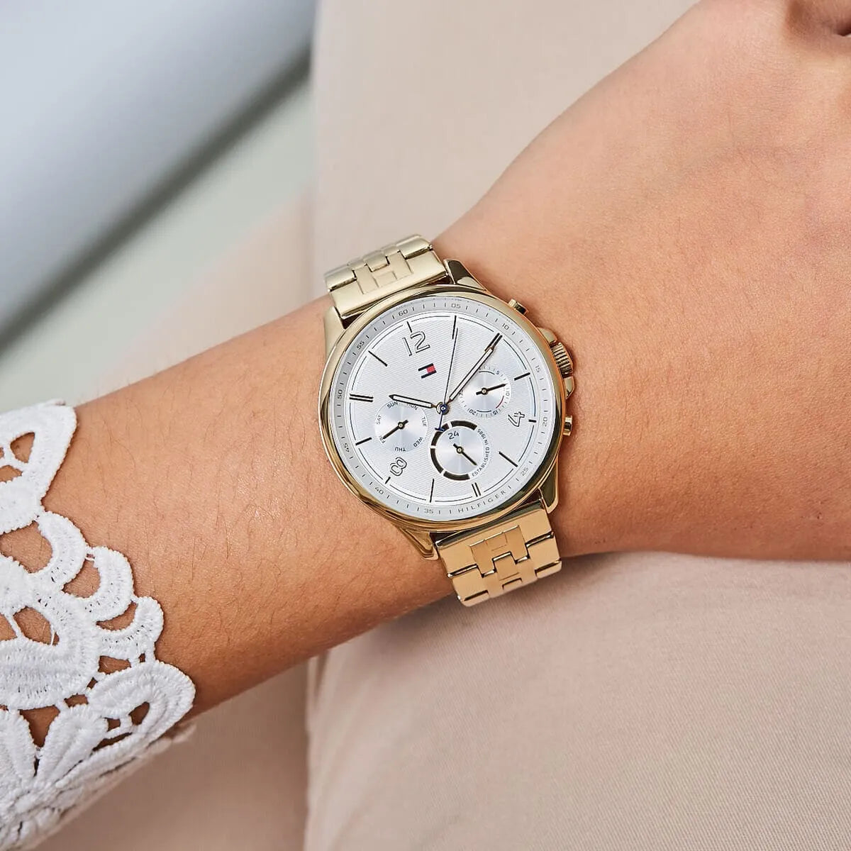 Tommy Hilfiger Harper chronograph watch worn on wrist with white dial and gold strap