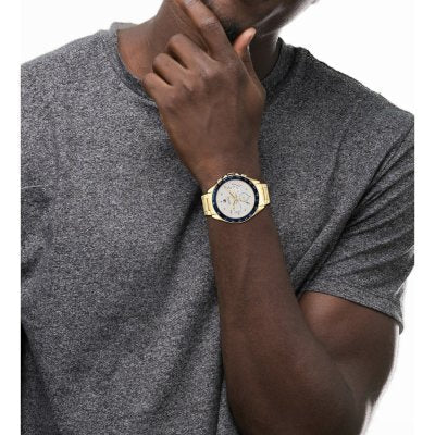 Tommy Hilfiger Owen gold chronograph watch worn on wrist with gray t-shirt