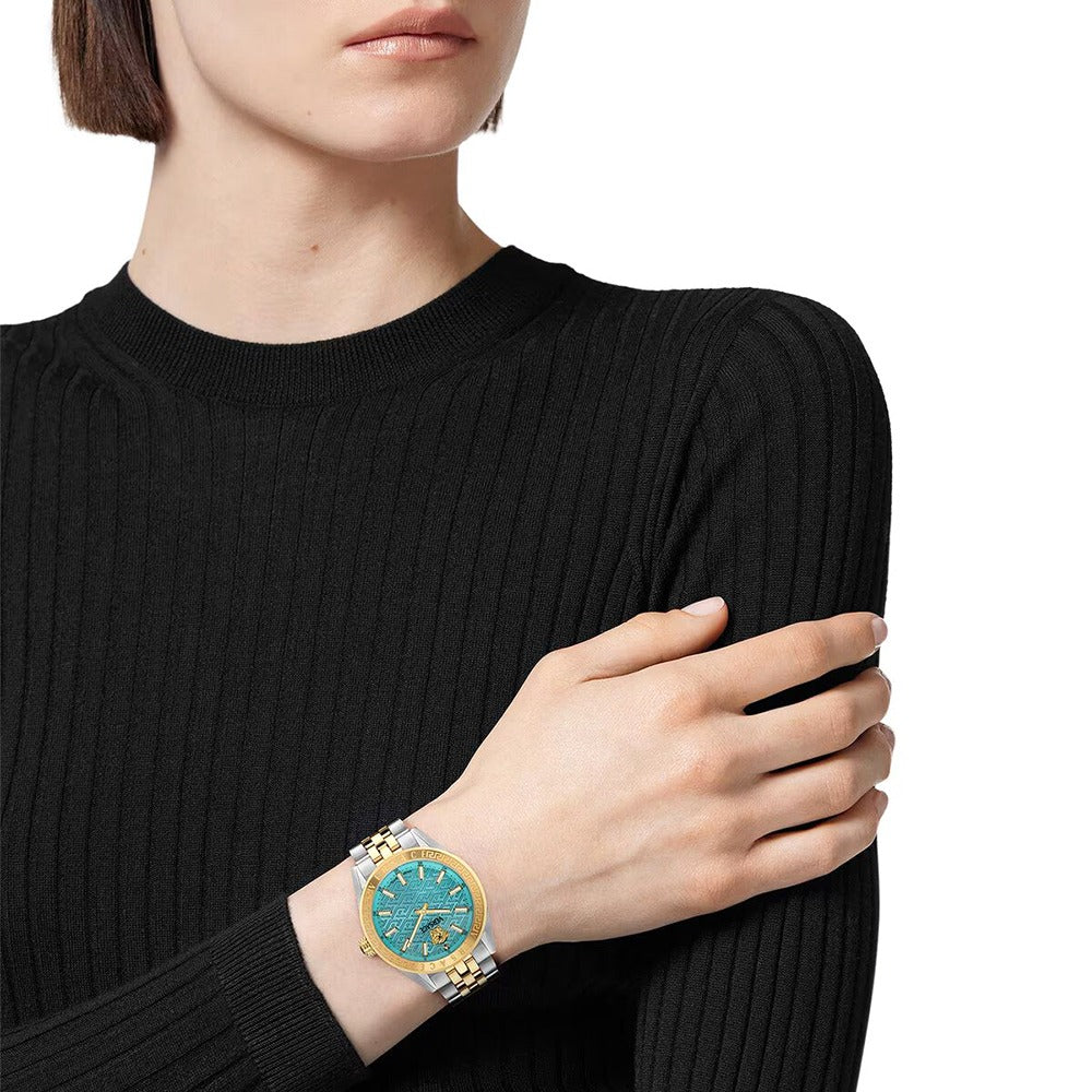 V Code watch with blue dial worn on woman's wrist over black long-sleeve shirt
