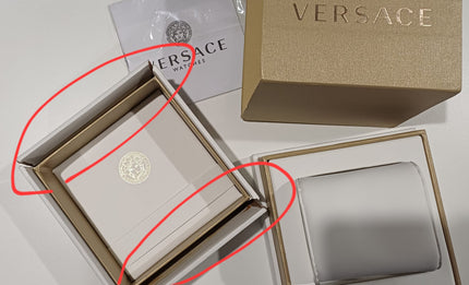 Versace watch box opened with branded presentation case and red marking indicators
